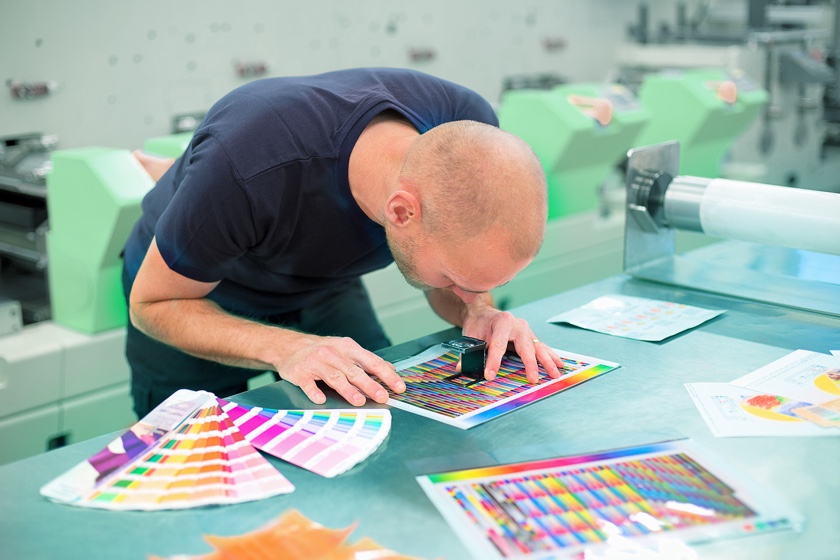 Mann schaut Farbe unter Lupe an.